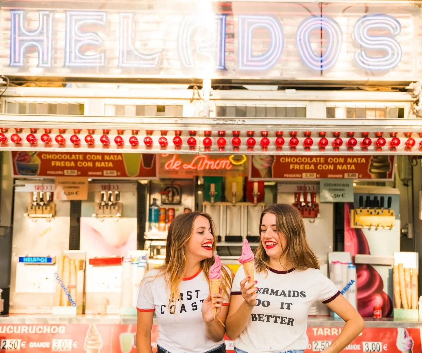 Dos mujeres felices sostienen helados en un parque de atracciones.